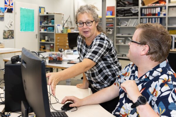 Medewerkster deelt kennis met een cliënt via de computer