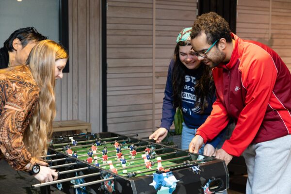 Jonge cliënten en begeleiders zijn aan het tafelvoetballen