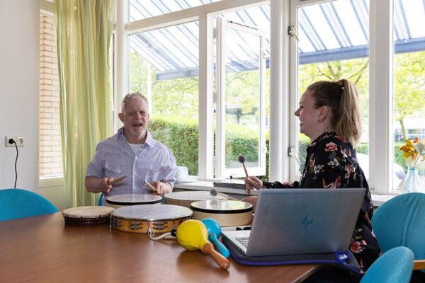 Begeleider en cliënt maken muziek aan tafel