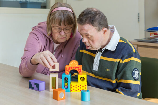 Twee mensen met bouwstenen aan tafel