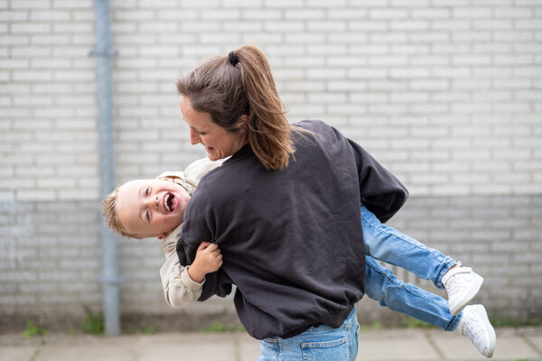 Kind lachend in armen begeleider