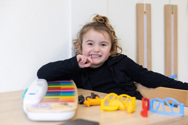 Lachend meisje met vinger in mond