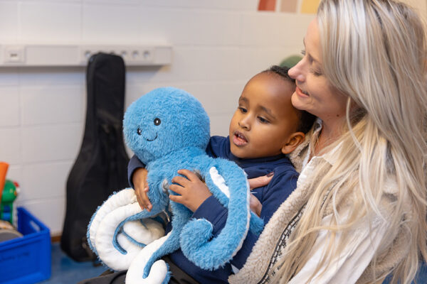 Kind p schoot bij begeleider et een pluche octopus