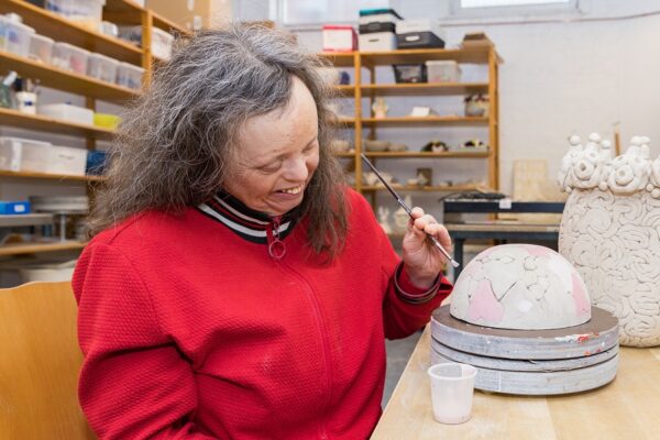 Cliënt beschildert keramiek tijdens dagbesteding