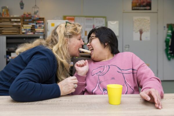 Begeleider en cliënt eten samen een rijstwafel tijdens de pauze