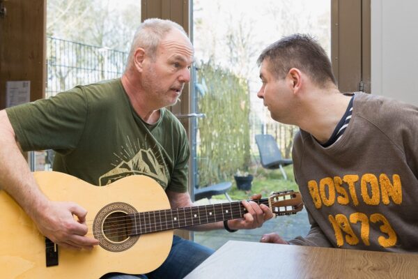 begeleider speelt gitaar voor cliënt