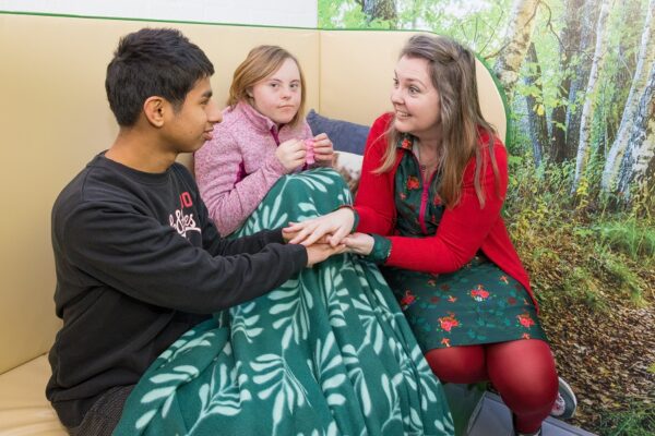 Cliënten en begeleider zitten samen op de bank tijdens dagbesteding